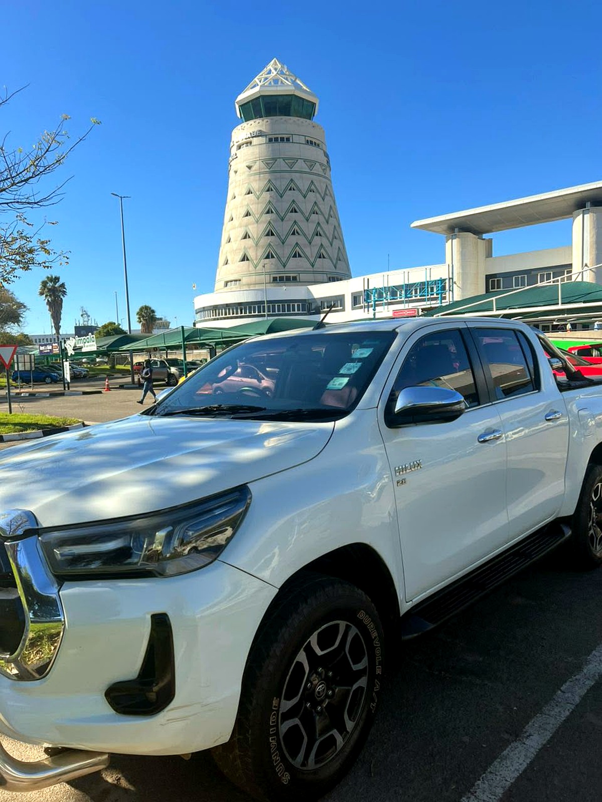 A VenMax Toyota Hilux parked in front of Harare's airport control tower