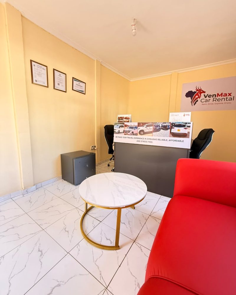 The VenMax Car Rental reception, with the company sign and a desk banner showing fleet vehicles